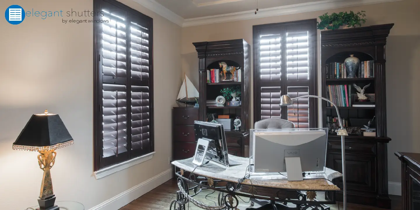 Elegant office interior featuring plantation shutters, stylish desk with computer, and decorative bookshelf, highlighting Cape Coral window treatment options.